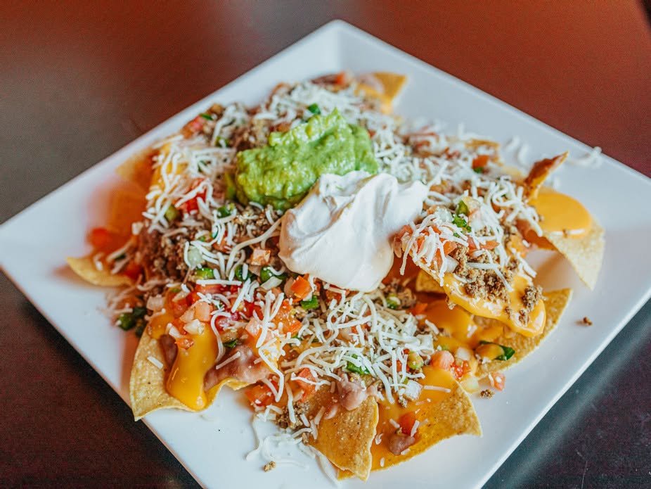 Loaded nachos with cheese, meat, guacamole, and sour cream